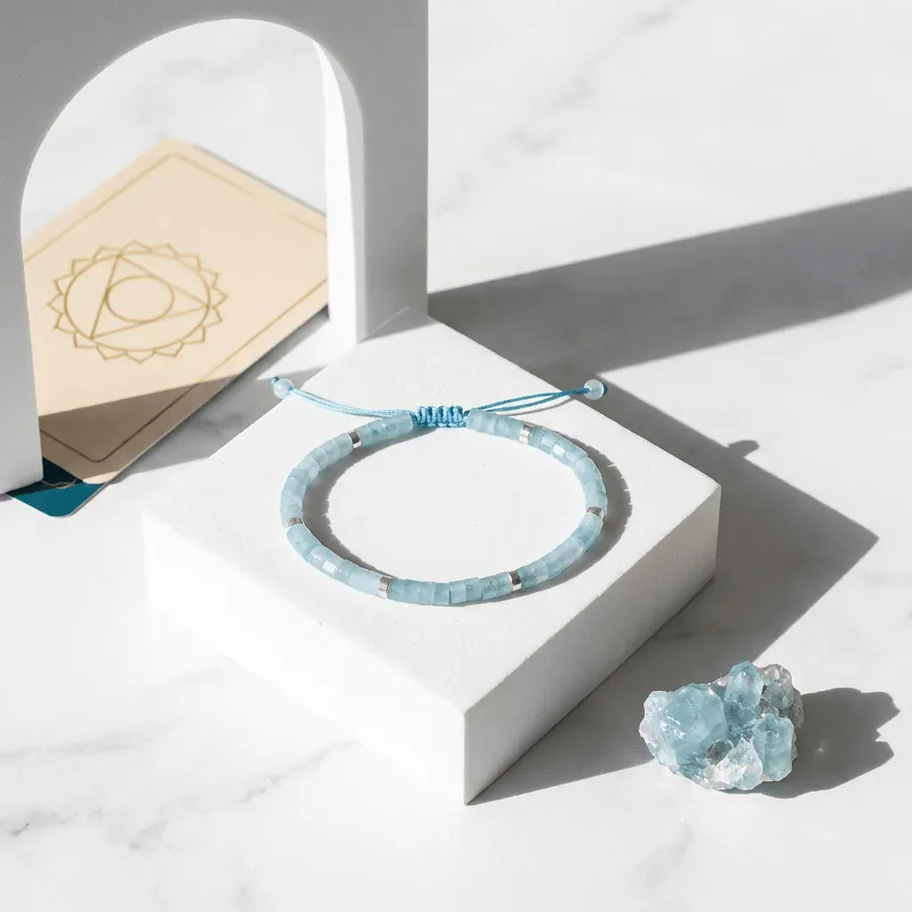 Blue beaded bracelet on a white stand with crystals and a wooden card in the background