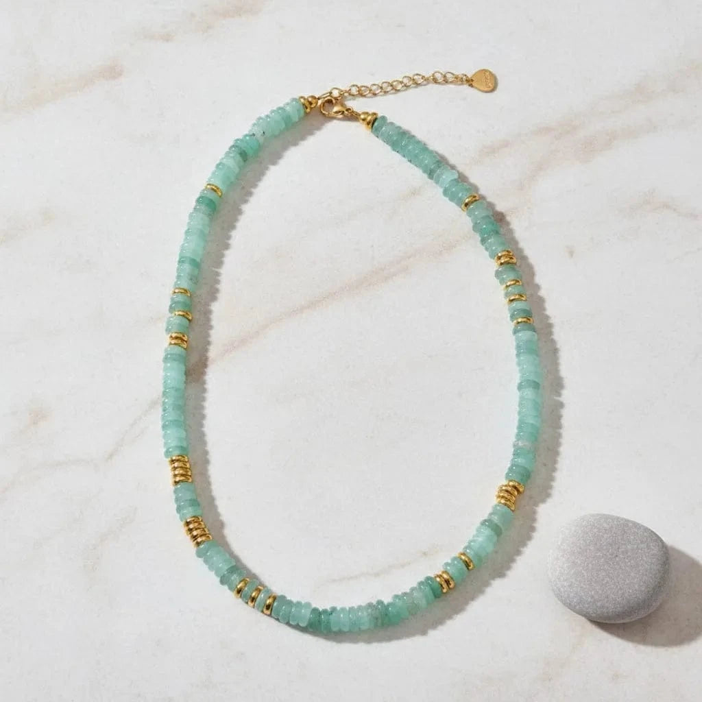 Necklace with light blue beads and gold accents on a white background