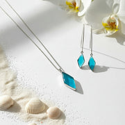 Turquoise diamond-shaped earrings on a white background with a plant branch.