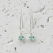 Pair of silver earrings with green gemstones on a textured gray background