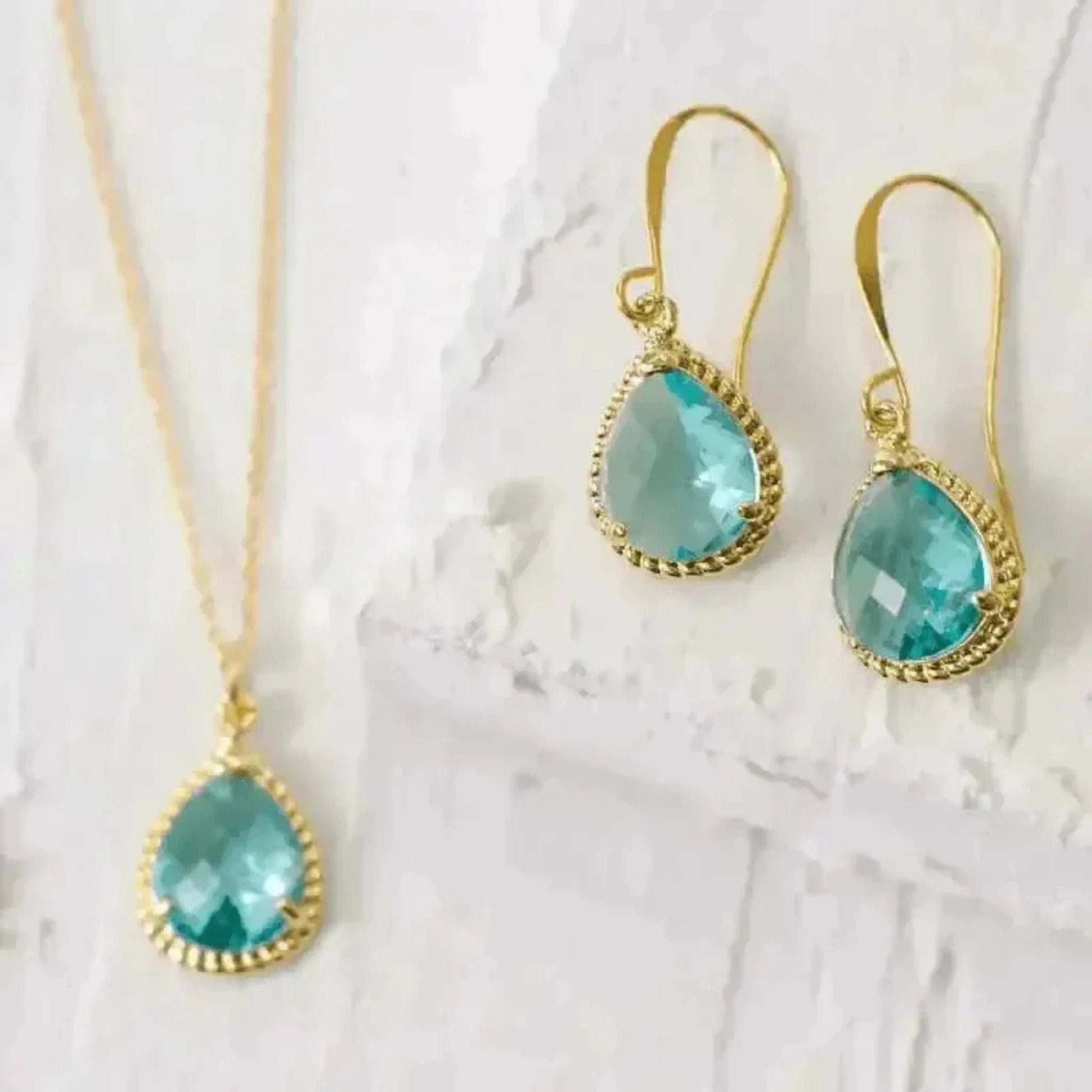 A pair of aqua color drop earrings with gold metalwork on a chain, displayed against a white background.