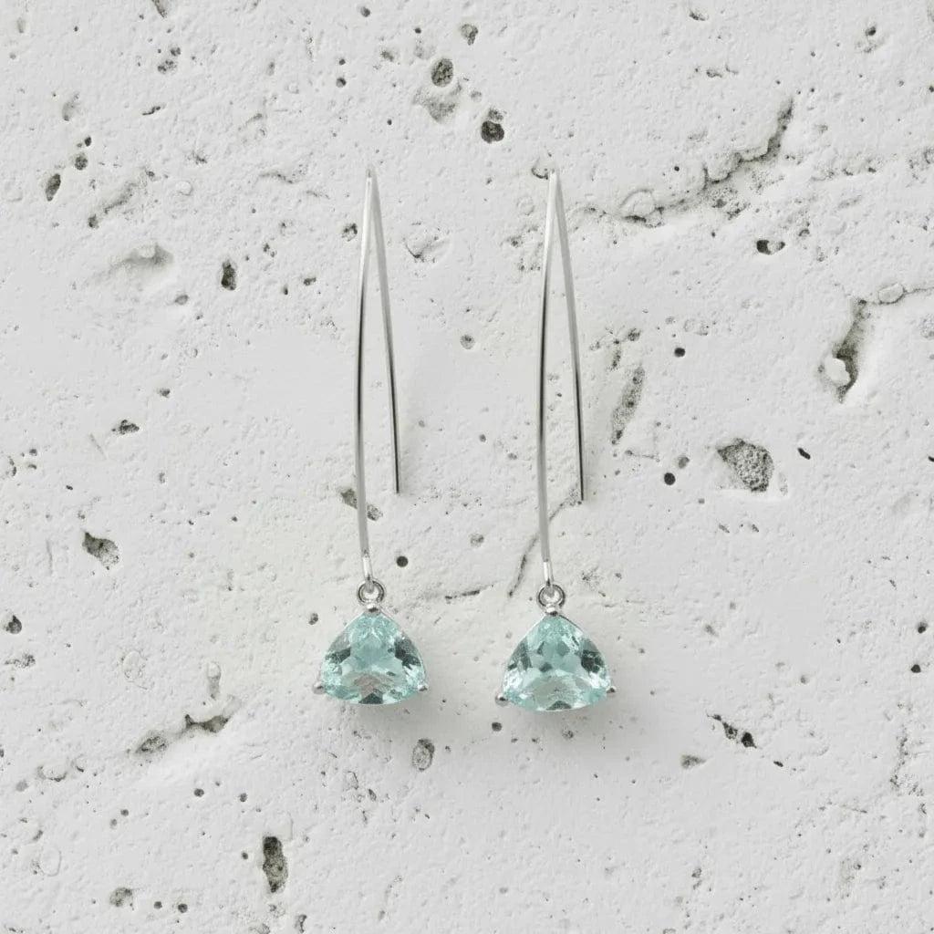 Pair of silver earrings with green gemstones on a textured gray background