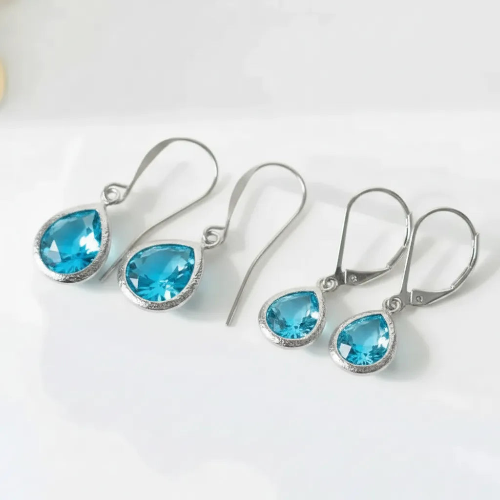 Pair of silver earrings with blue teardrop-shaped gemstones on a white background