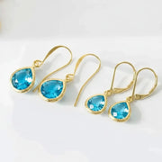 Gold earrings with blue gemstones on a white background