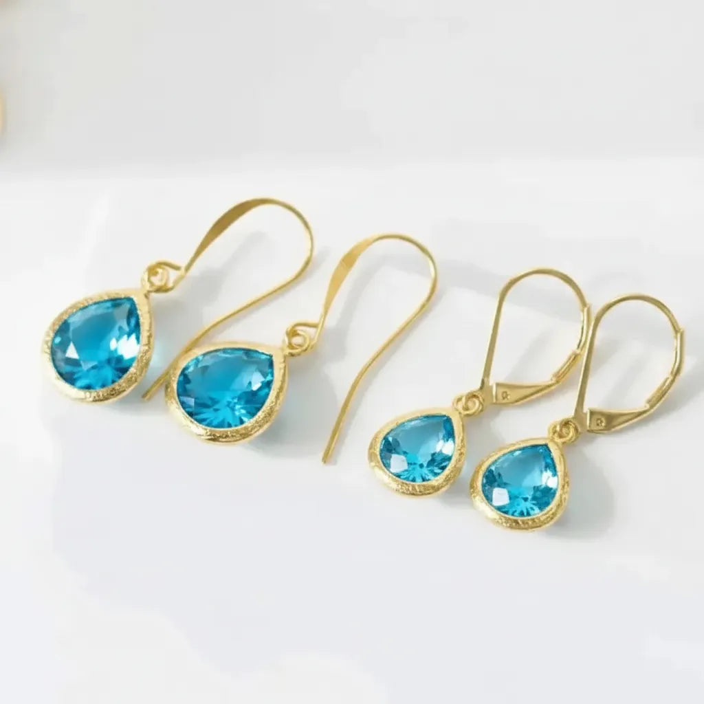 Gold earrings with blue gemstones on a white background