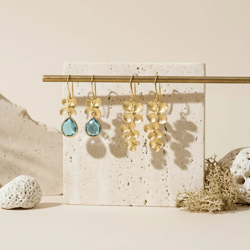 Mystic Soul Jewelry Aqua Orchid earrings displayed on a stand with decorative stones and text about the product.