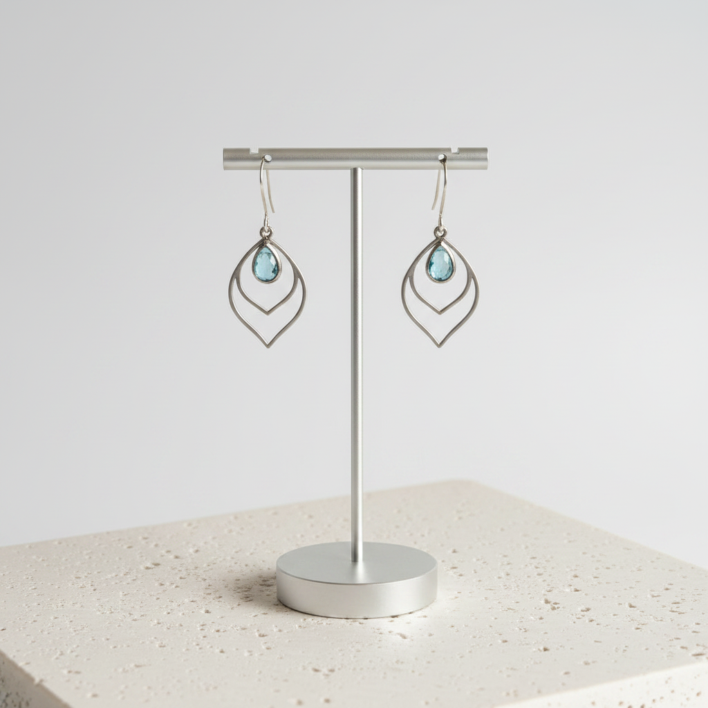 Aqua blue faceted glass teardrop earrings in silver on a card with green gift bag