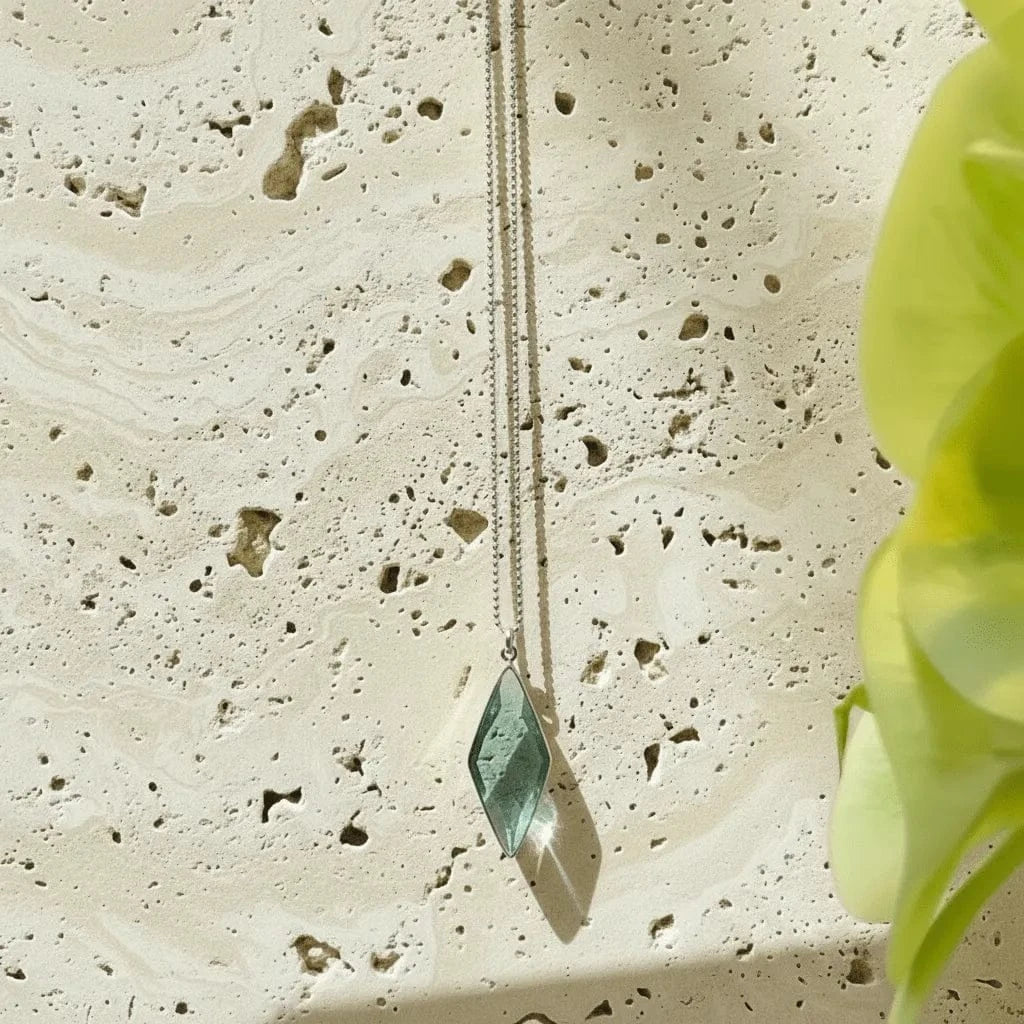 Necklace with a green pendant on a textured stone surface
