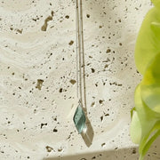 Necklace with a green pendant on a textured stone surface