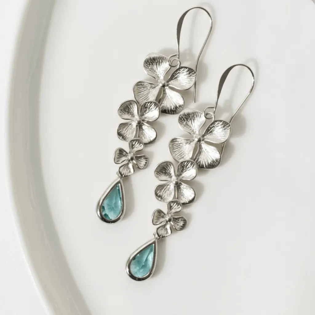 Silver floral earrings with turquoise drops on a white background