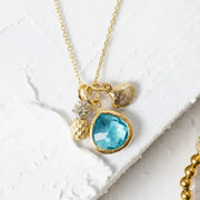 Gold necklace with a blue pendant on a white textured surface