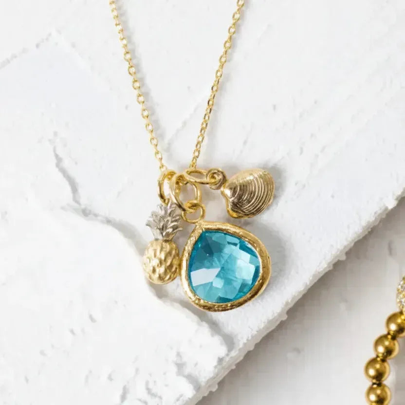 Gold necklace with a blue pendant on a white textured surface