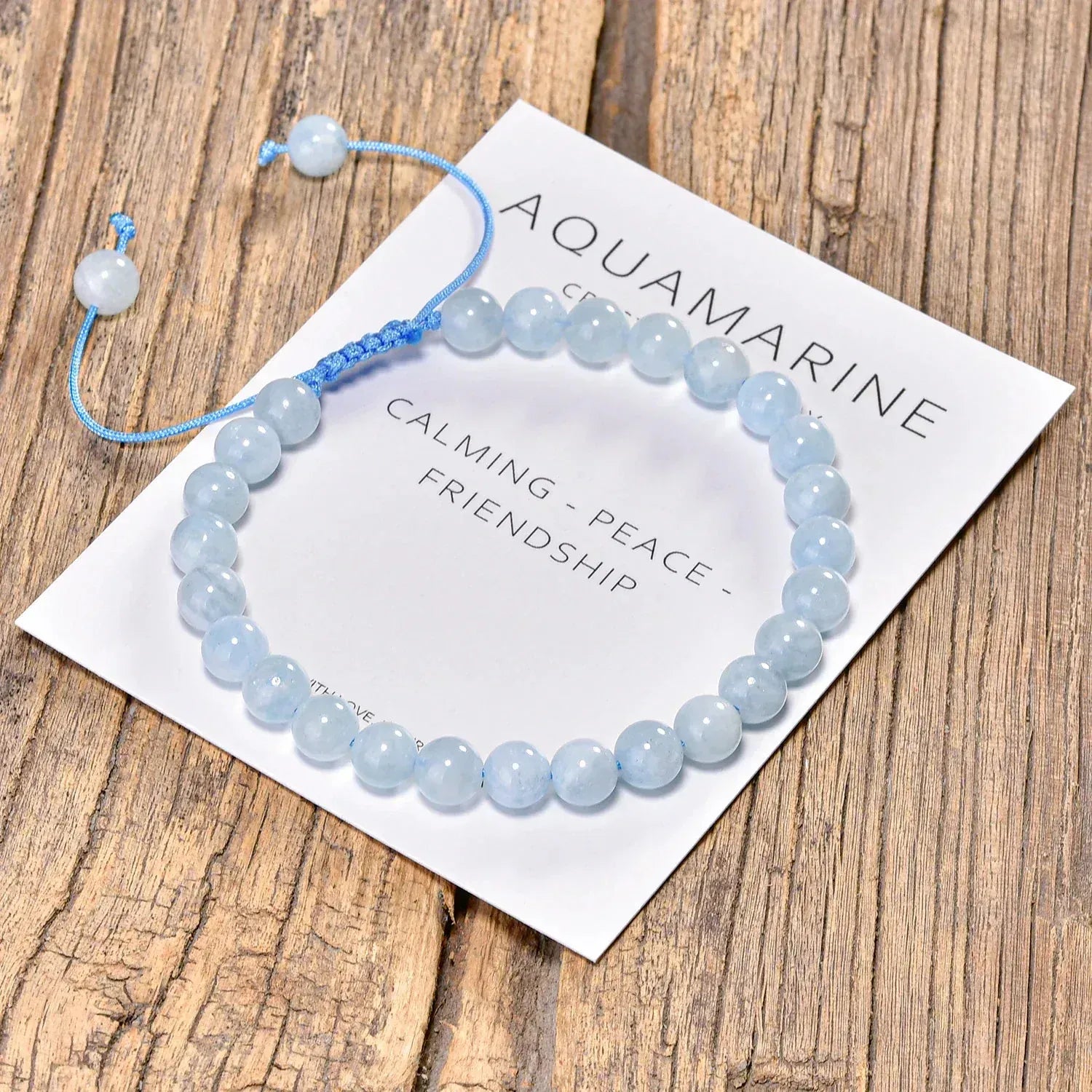 Aquamarine bracelet on a card with text on a wooden surface
