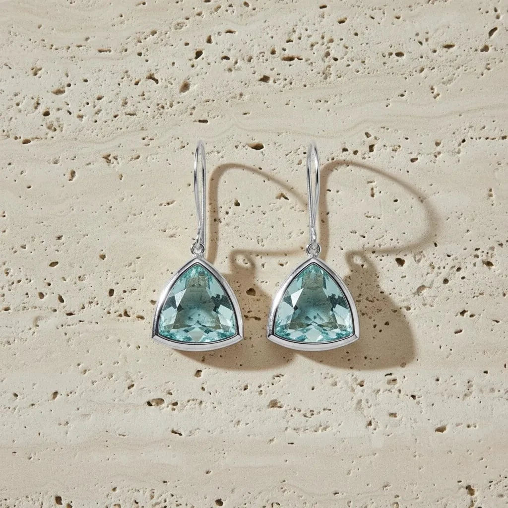 Teardrop-shaped turquoise earrings on a beige stone background