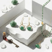 Jewelry set with green stones on a white surface, featuring text about TV shows and a call to shop.