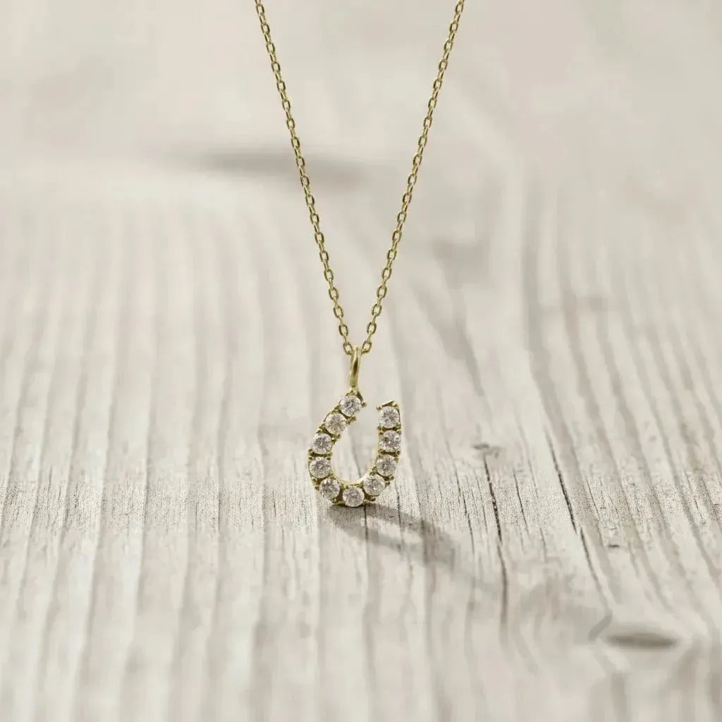 Gold necklace with a teardrop-shaped pendant on a wooden surface
