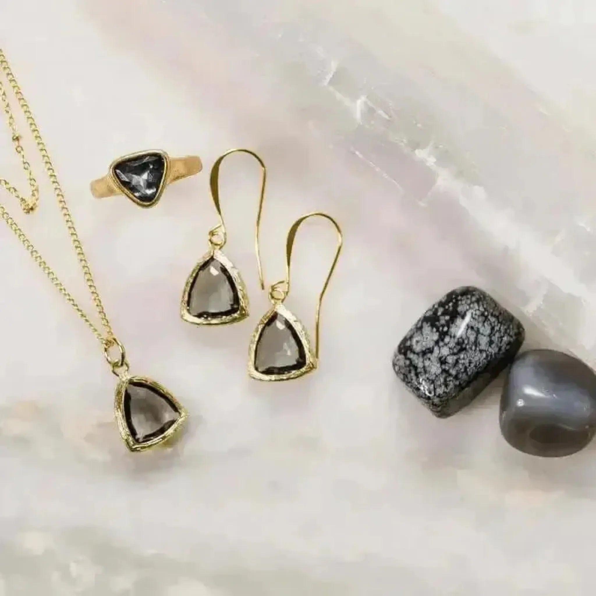 grey gold jewelry set with necklace earrings and ring in flat lay with crystals