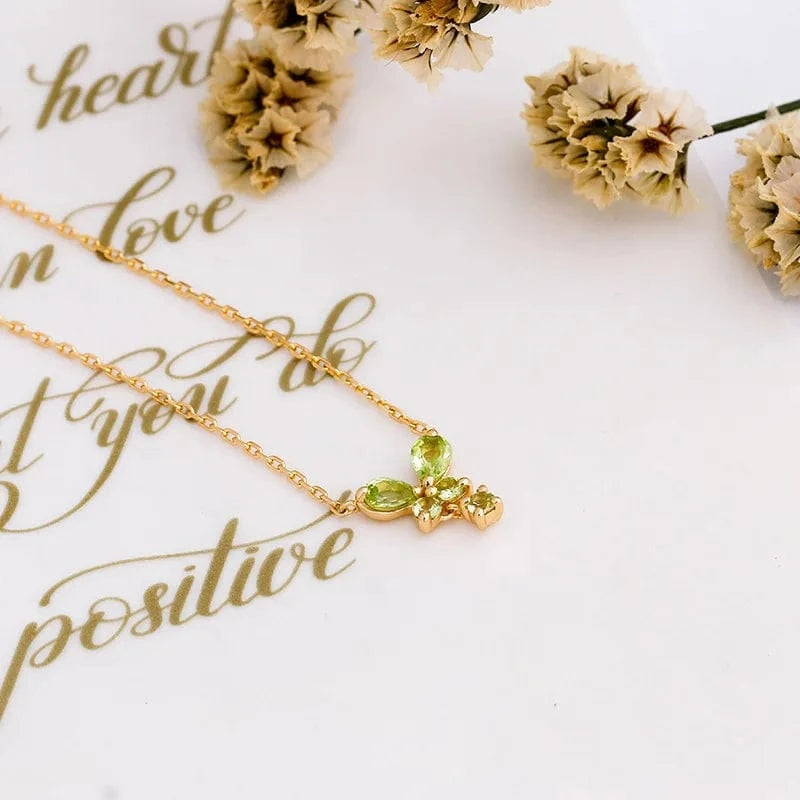 Gold necklace with green gemstone butterfly pendant on a white background with gold text