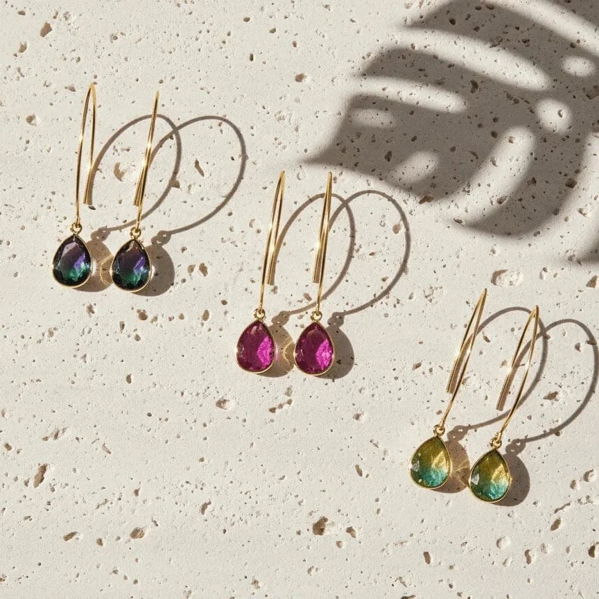Set of gold earrings with colorful gemstones on a textured surface
