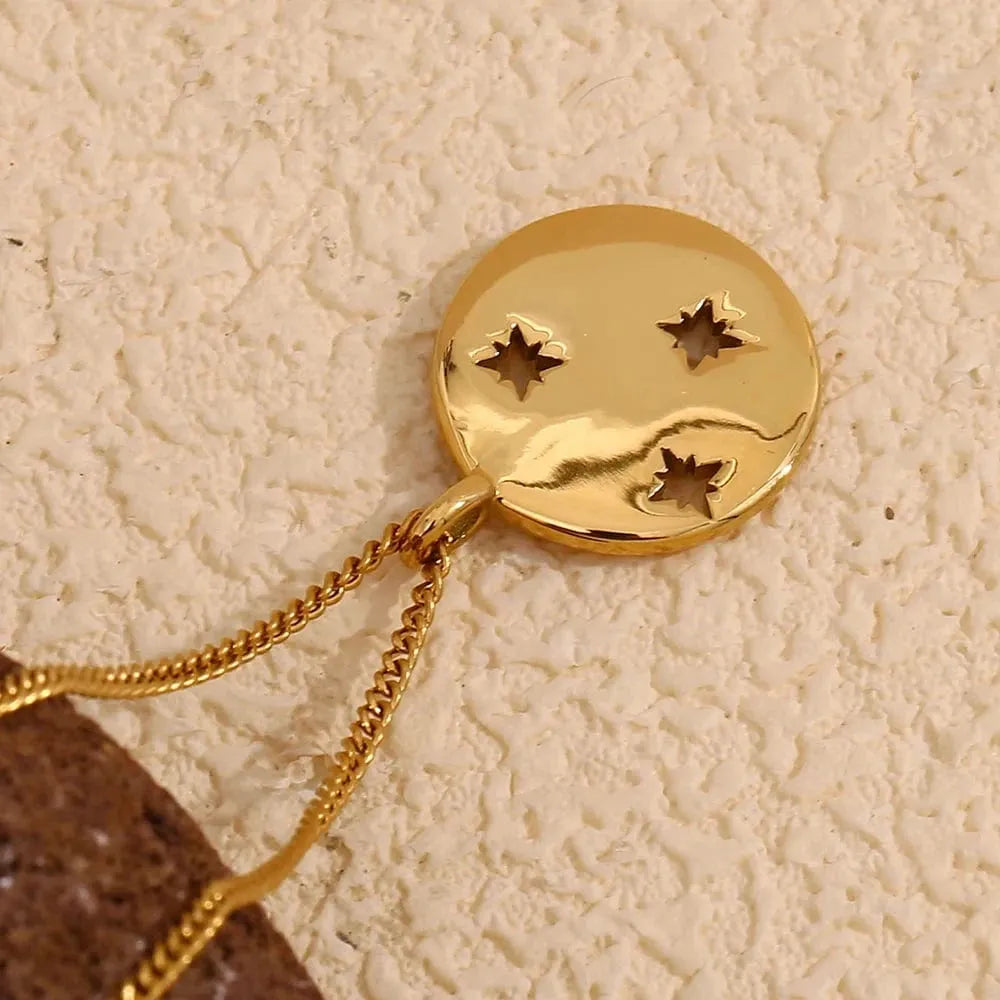 Gold pendant with star designs on a textured beige background
