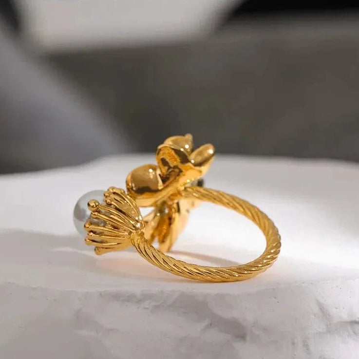 Gold ring with intricate design on a white marble surface