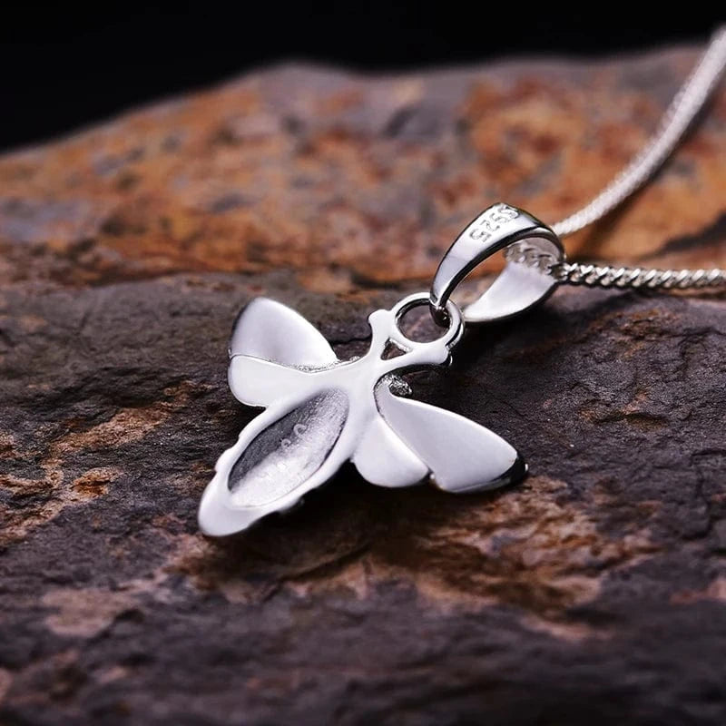 Silver butterfly pendant on a dark stone surface