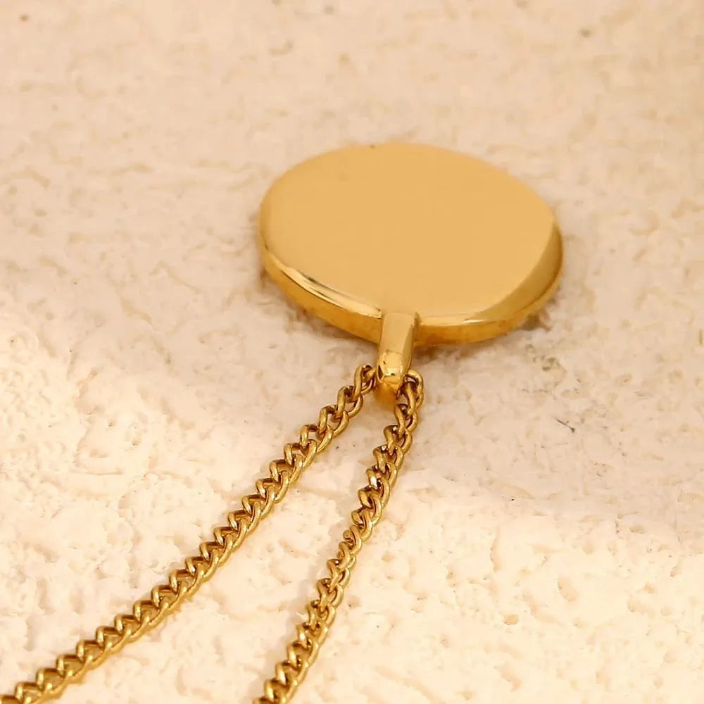 Gold necklace with a round pendant on a beige background