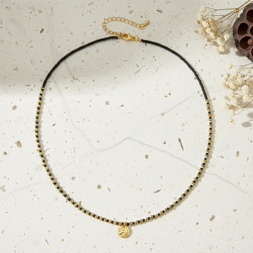 Necklace with black cord and gold beads on a white background