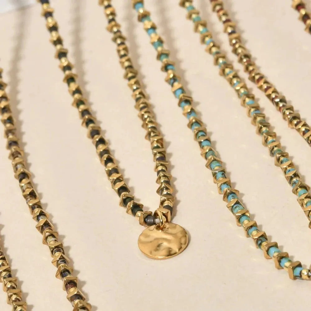 Three beaded necklaces with gold and turquoise beads on a light background