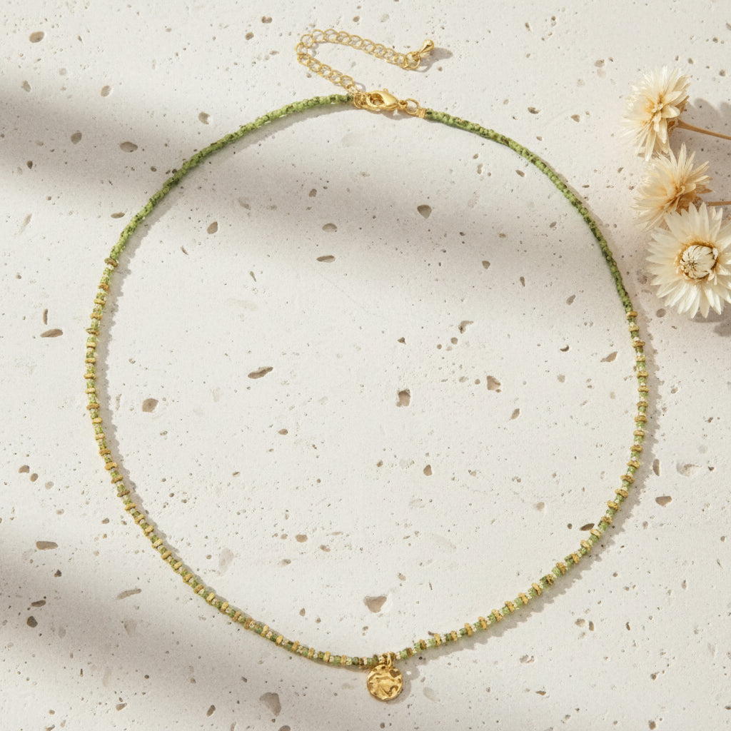 Necklace with green beads and a gold clasp on a white background
