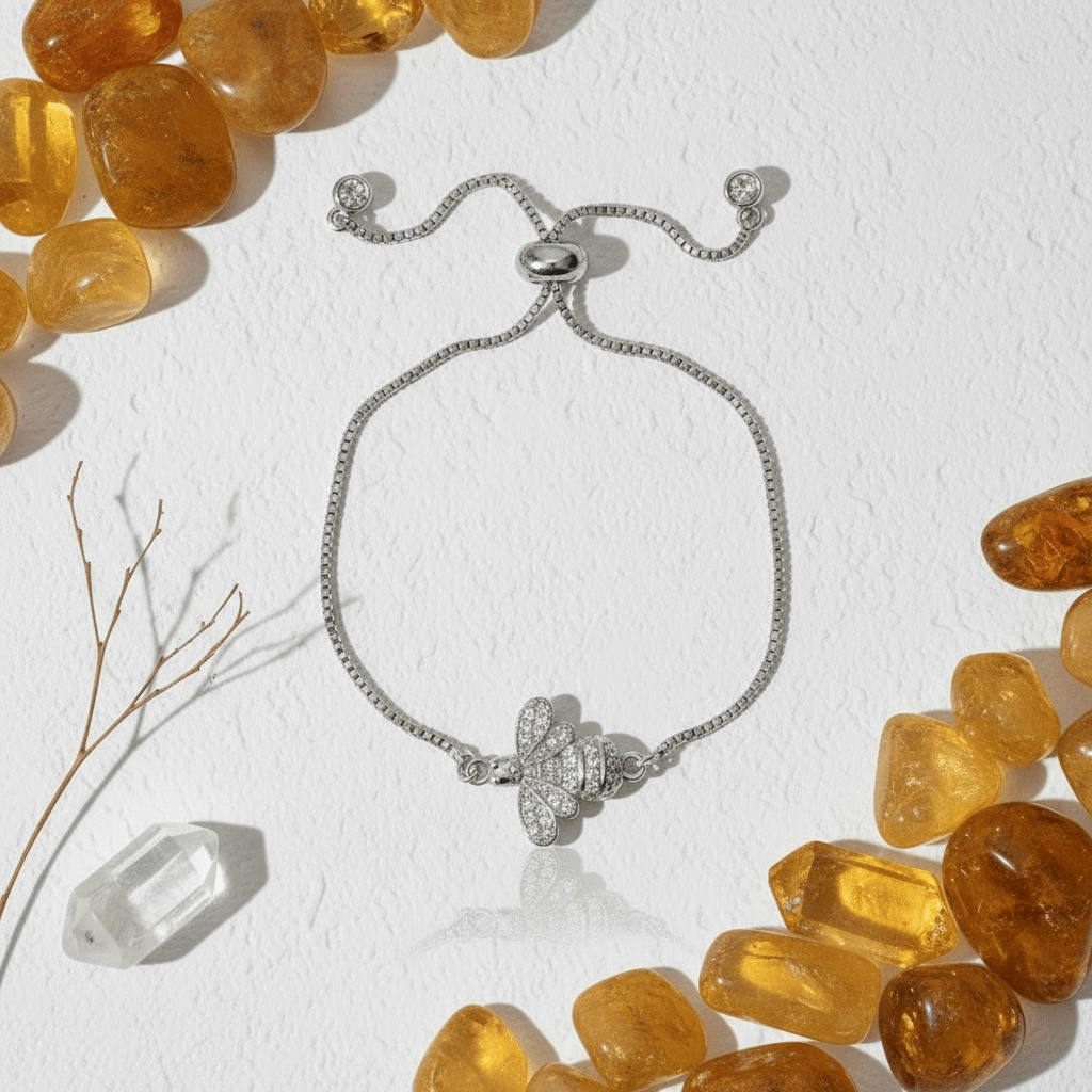 Gold bracelet with a butterfly charm on a white background with pink stones and branches.