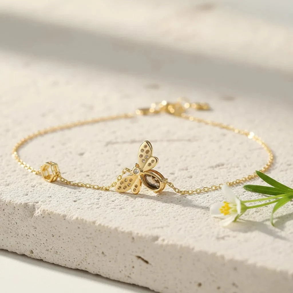 Gold bracelet with butterfly charm on a light background