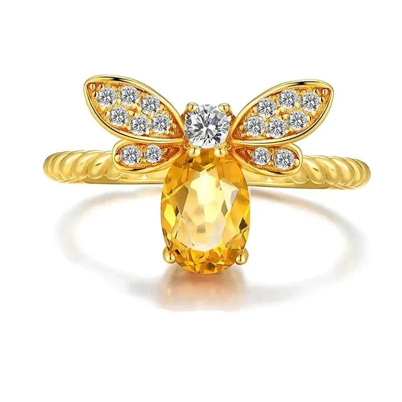 Gold bee-shaped ring with a yellow gemstone on a white background