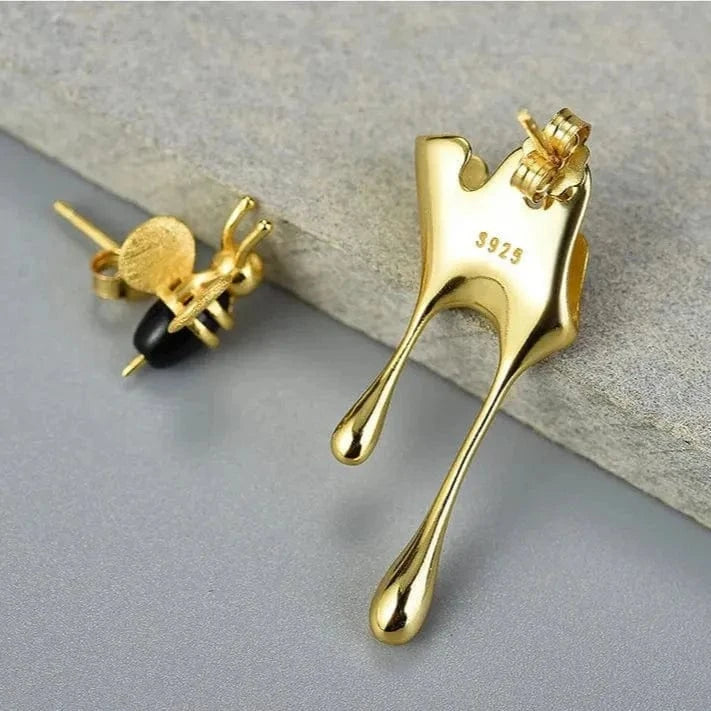 Gold bird-shaped earrings on a gray surface