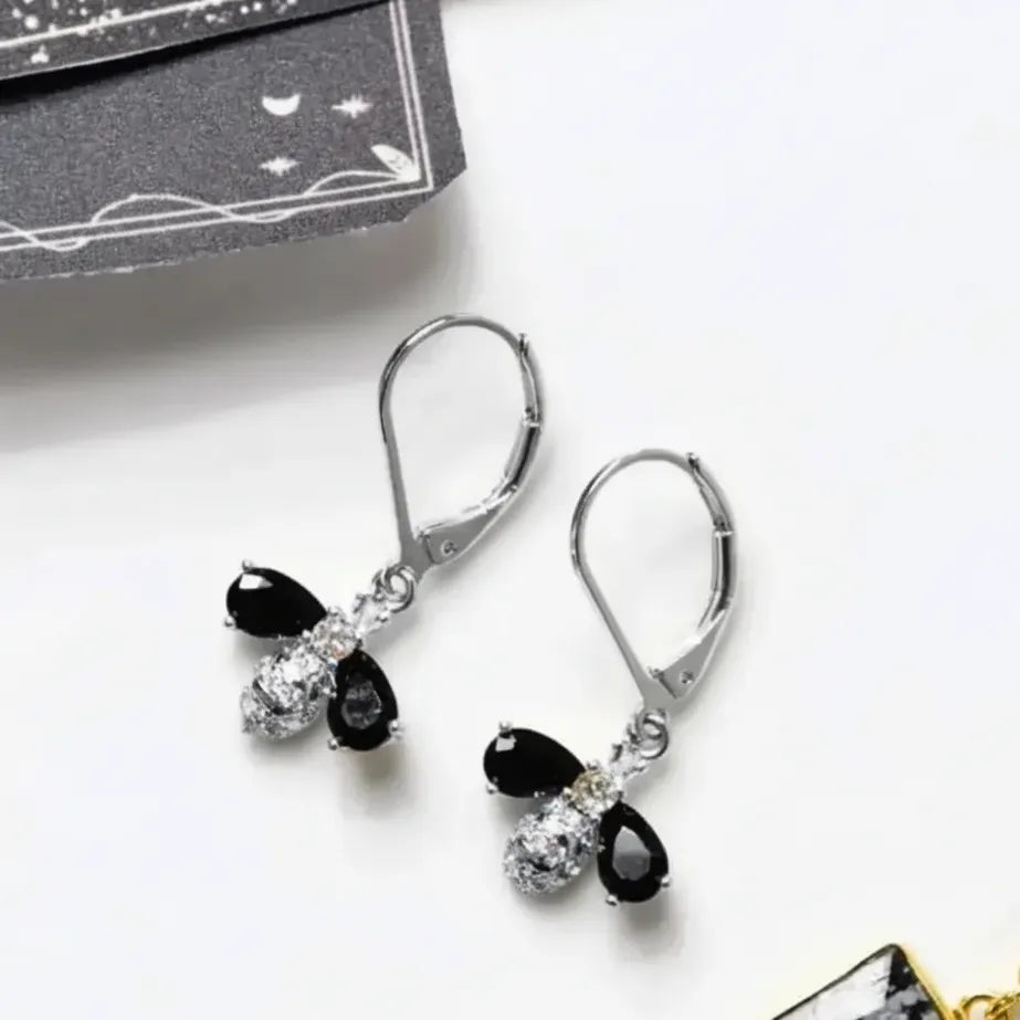 Silver earrings with black and clear gemstones on a white background