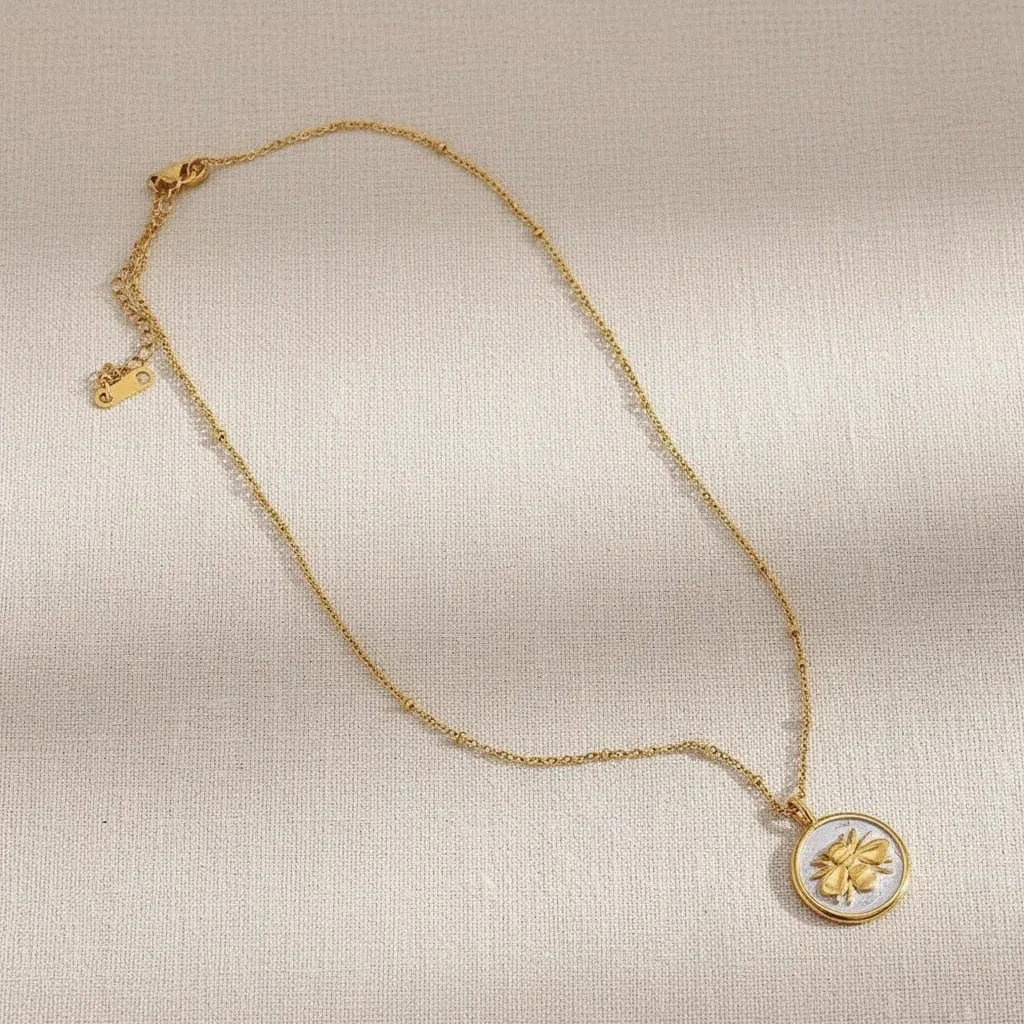 Gold necklace with a decorative pendant on a textured surface