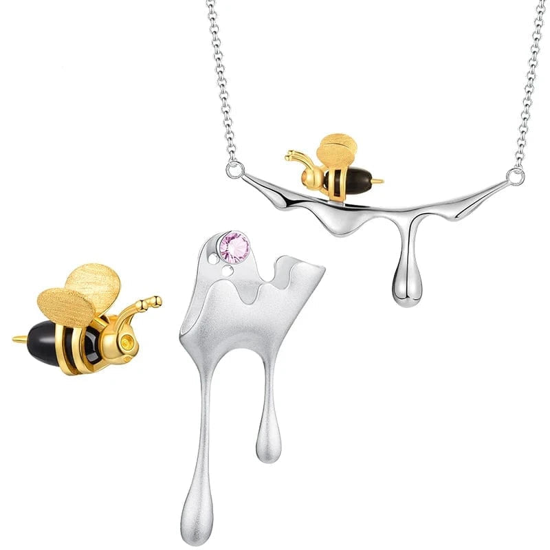 Silver and gold bee-shaped necklace with a pink gemstone on a white background