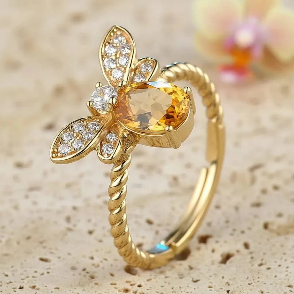 Gold bee-shaped ring with a central gemstone on a dark background