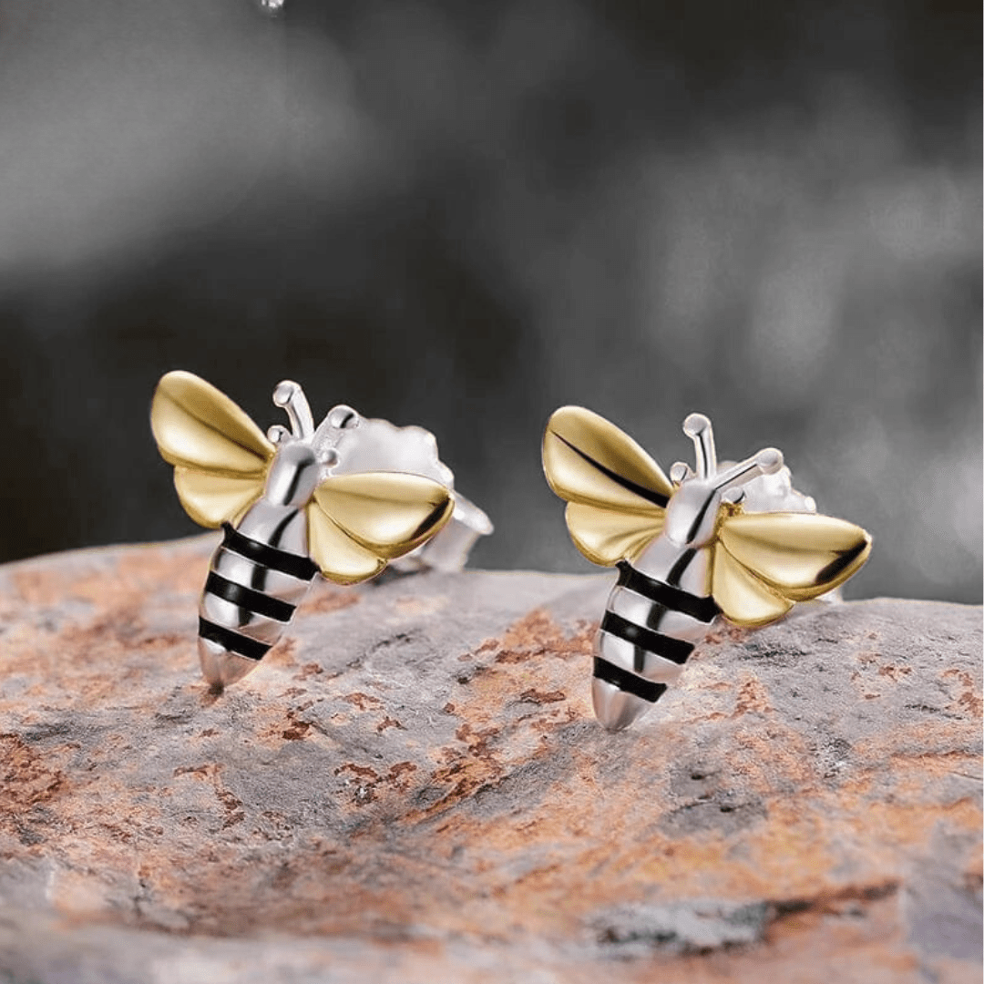 Bee-shaped earrings on a textured surface with a blurred background