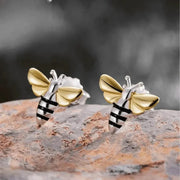 Bee-shaped earrings on a textured surface with a blurred background