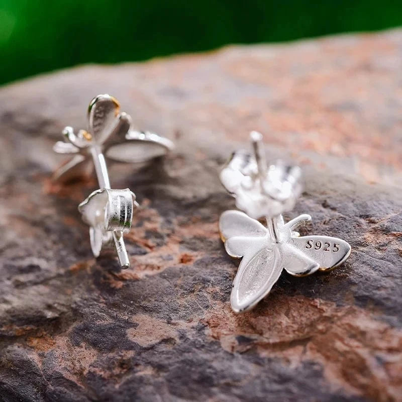 Silver butterfly earrings on a textured stone surface