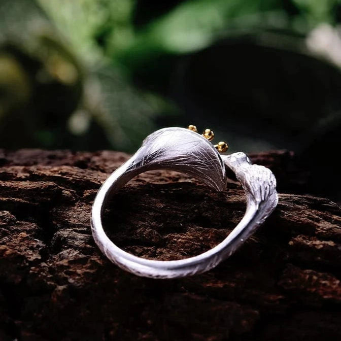 Silver ring with gold accents on a wooden surface