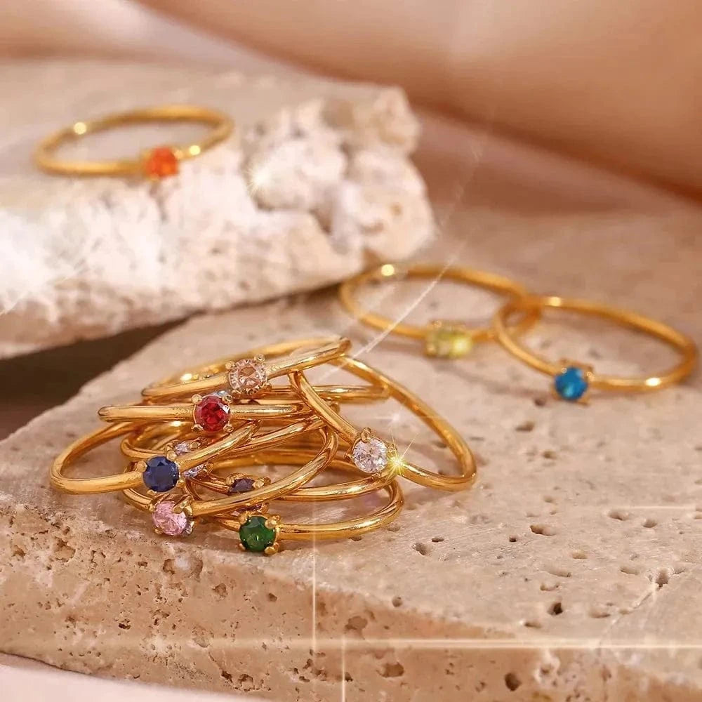 Gold rings with colorful gemstones on a textured surface