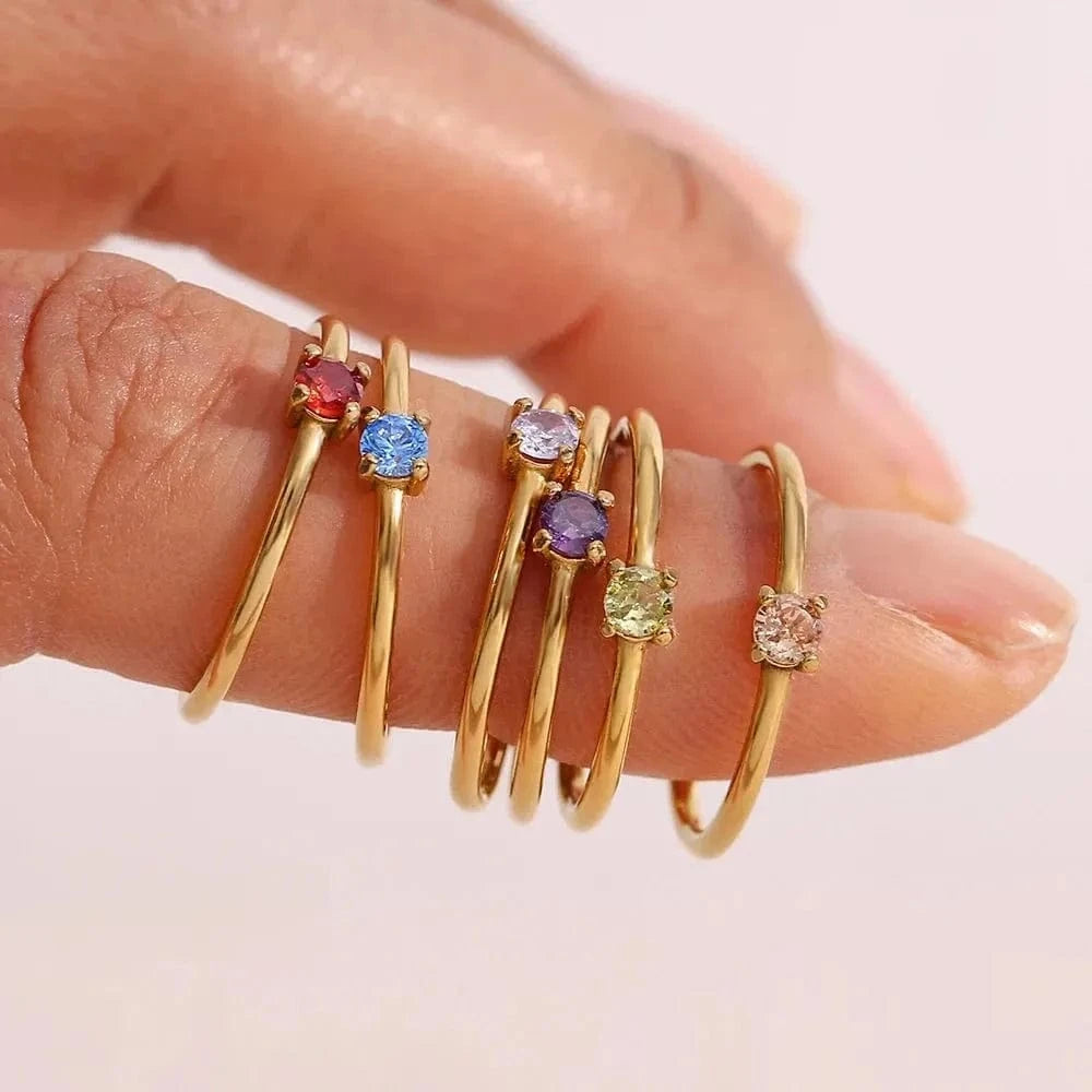 Gold rings with colorful gemstones on a hand against a light background