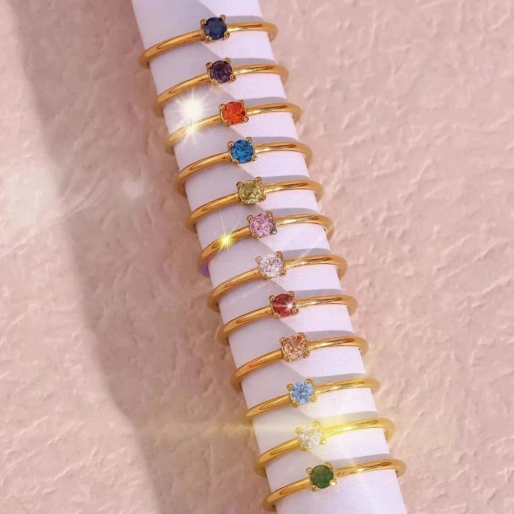 Set of gold rings with colorful gemstones on a white surface