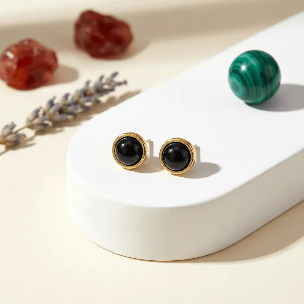 Gold earrings with red stones on a white surface with decorative elements.