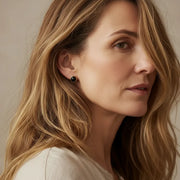 Woman wearing a black agate stud earring — root chakra jewelry for grounding