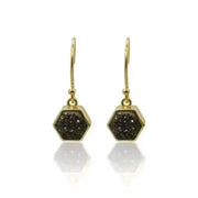 Gold hexagonal earrings with black druzy stones on a white background