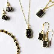 Gold and black jewelry set including necklace, earrings, and bracelet on a white background