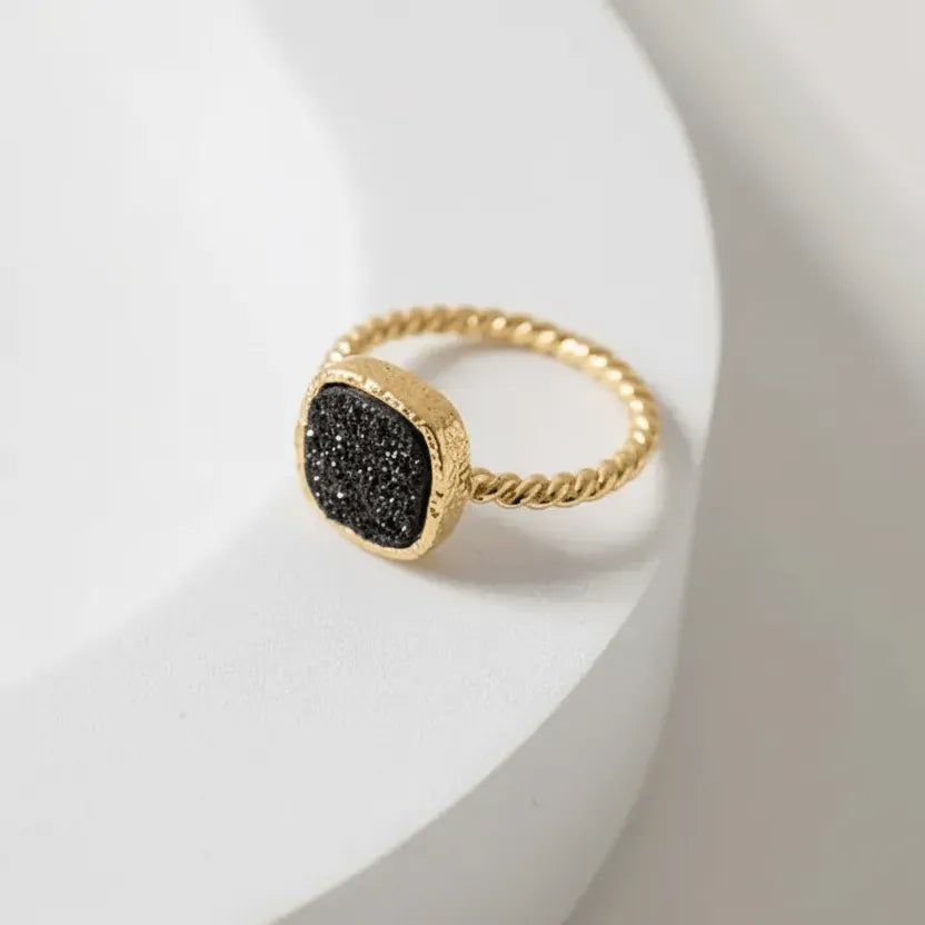 Gold ring with black druzy stone on a white background